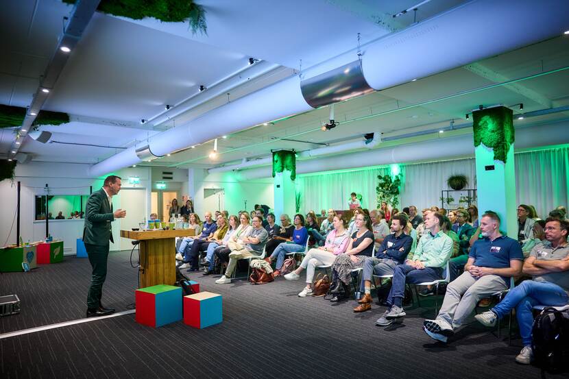 Een spreker staat voor een zaal vol publiek