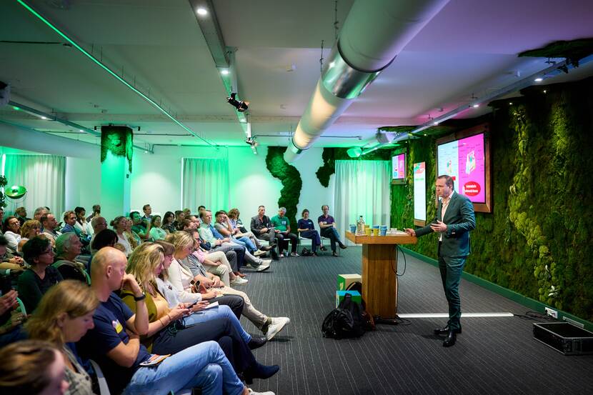 Een spreker staat voor een zaal met publiek