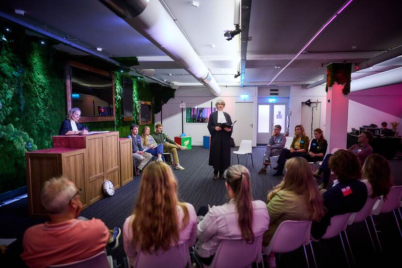 Personen in rechtskledij staan voor een zaal met publiek